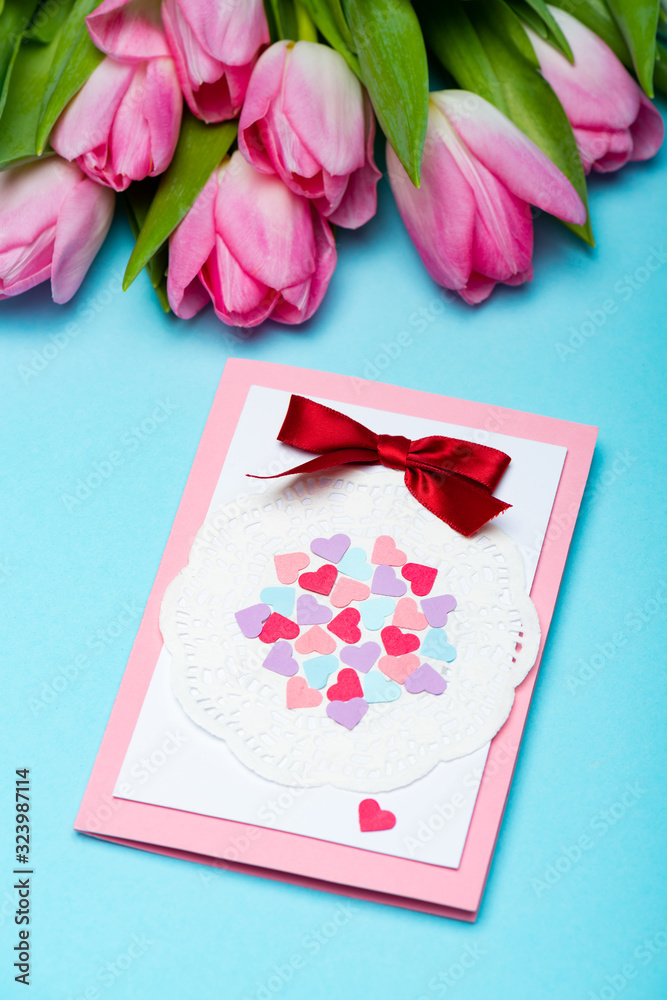 Greeting card near bouquet of tulips on blue background