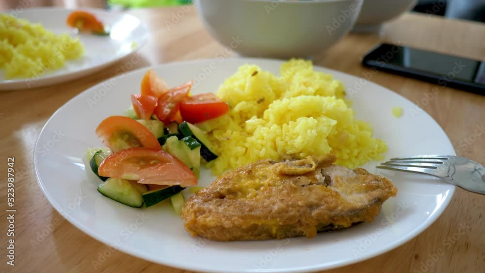 Powdered curcumin turmeric rice with fried fish, sliced tomato and cucumber slices. Delicatessen food. Eating together appetizer concept Powdered curcumin turmeric rice with fried fish, sliced tomato and cucumber slices. Delicatessen food. Eating together appetizer concept