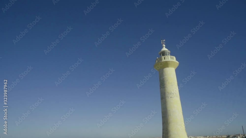  boy with yellow sweatshirt running in a lighthouse with clear sky