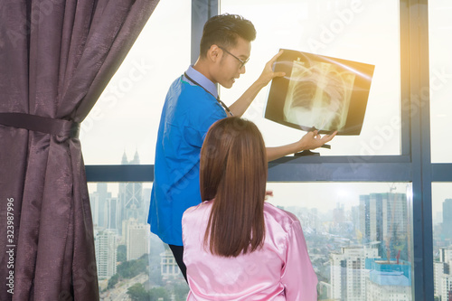 Asian doctor explain to his patient using X-Ray film.