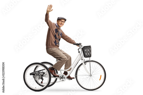 Happy elderly man riding a tricycle and waving at camera