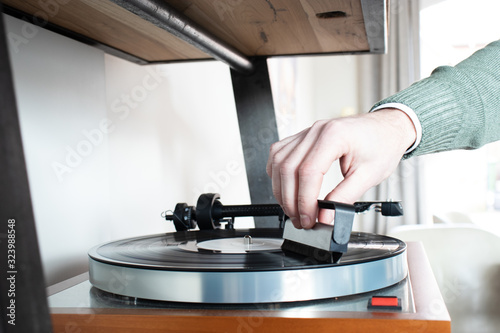 man is using an anti static vinyl brush on a record music player. Cleaning lp