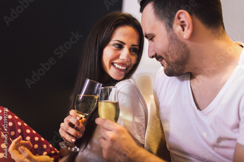 Smiling couple drinking champange while lying in bed