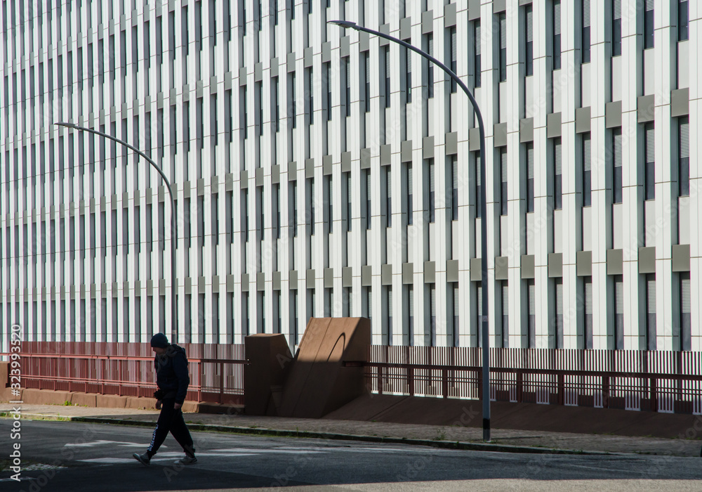A lonely man crosses the street early Sunday morning, in the shadow of a closed office building A lonely man crosses the street early Sunday morning, in the shadow of a closed office building