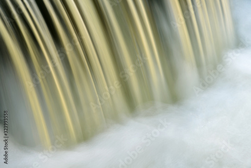 Bond falls cascade captured with motion blur and illuminated by reflected color from sunlit autumn trees  Michigan s Upper Peninsula.