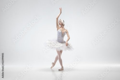 Fototapeta Naklejka Na Ścianę i Meble -  Graceful classic ballerina dancing isolated on white studio background. Woman in tender clothes like a white swan characters. The grace, artist, movement, action and motion concept. Looks weightless.