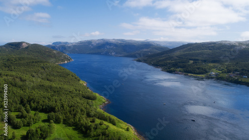Aerial view of mountains and fjord in Norway. Clouds and blue sky.