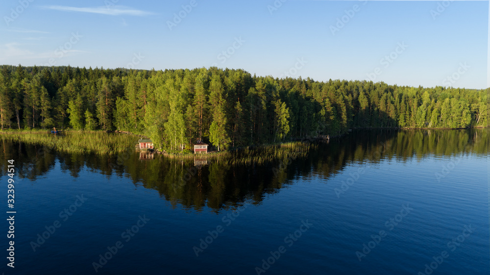 Aerial view of blue lake, hut and green forest on a summer day in Finland.