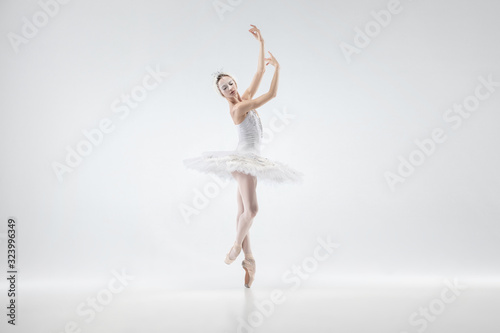 Graceful classic ballerina dancing isolated on white studio background. Woman in tender clothes like a white swan characters. The grace, artist, movement, action and motion concept. Looks weightless.