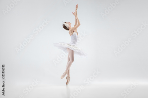 Graceful classic ballerina dancing isolated on white studio background. Woman in tender clothes like a white swan characters. The grace, artist, movement, action and motion concept. Looks weightless.