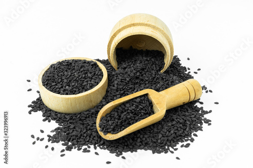 Black Sesame seeds in wooden bowl and spoon isolated on white background.Organic natural sesame seeds and extract oil concept