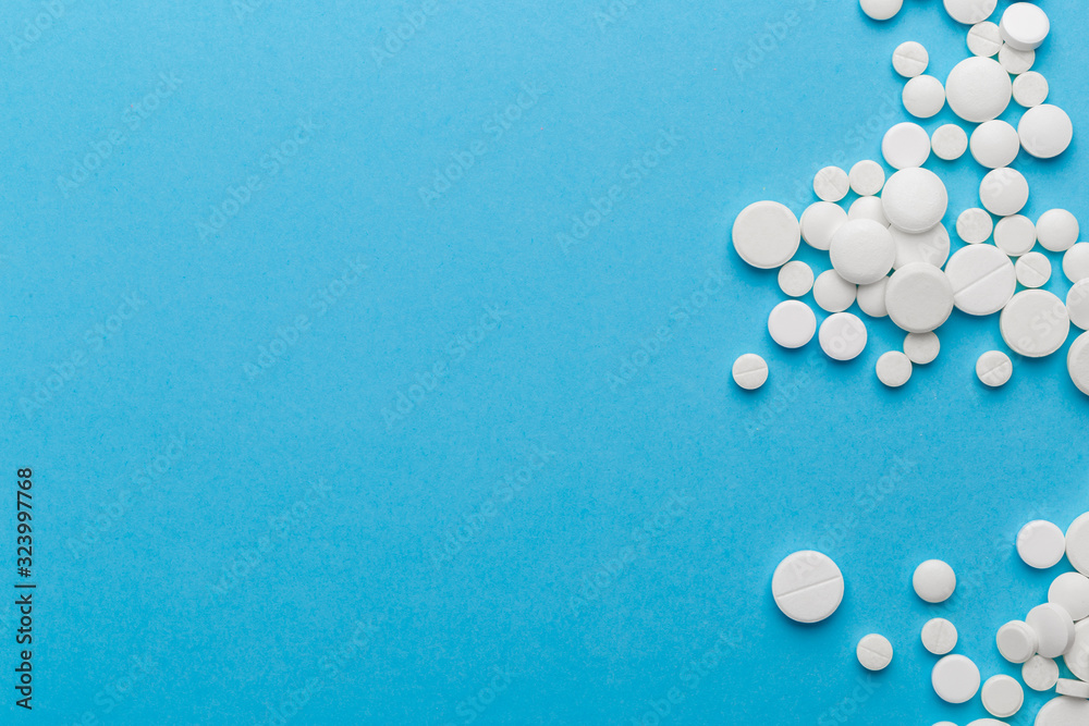 scattered white pills on a blue table. Layout for special offers such as advertising or other ideas. The concept of medicine, pharmacy and healthcare. Space for copy. flat lay for text or logo.