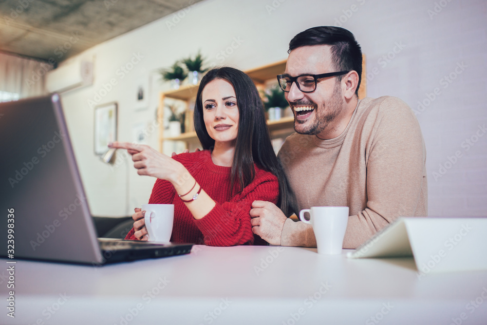 Happy couple doing business together working at small office on the laptop Happy couple doing business together working at small office on the laptop