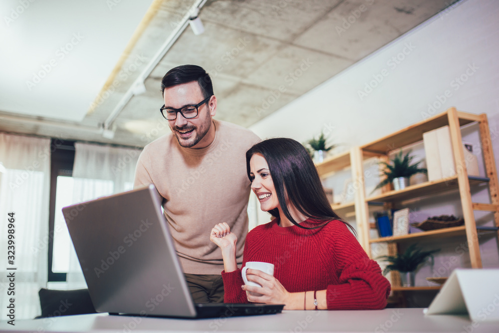 Happy couple doing business together working at small office on the laptop