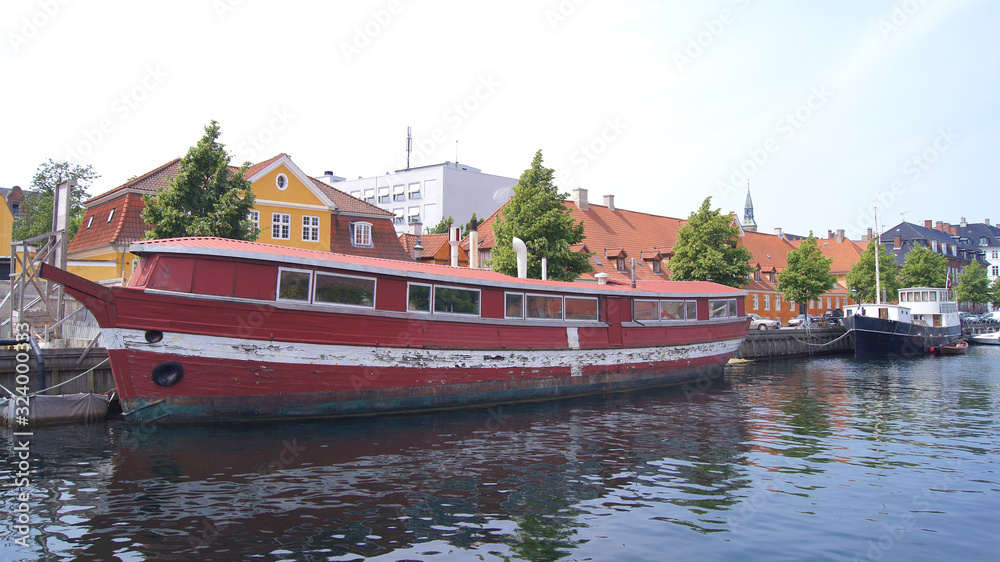 COPENHAGEN, DENMARK - JUL 06th, 2015: Red Floating house on city canal. Wodden House boat moored in a channel