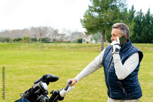 Senior using his smartphone while playing a game of golf