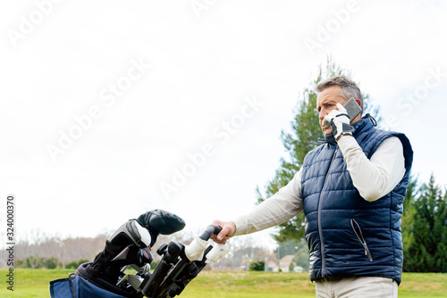 Senior using his smartphone while playing a game of golf
