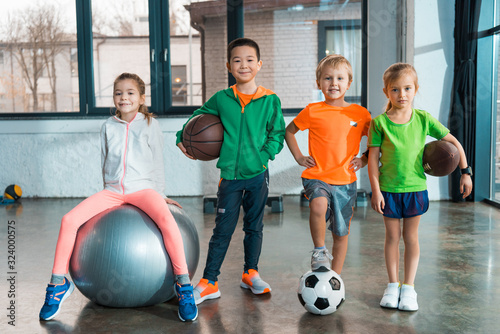 Front view of Child sitting on fitness ball next to multiethnic children with balls in gym