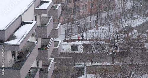 Heavy snow falling and wind blowing snow flakes sideways, against a pattern of open balconies of an apartment building in Bucharest, Romania.