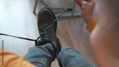 Boy tying shoelaces at school. Child developing motor skills