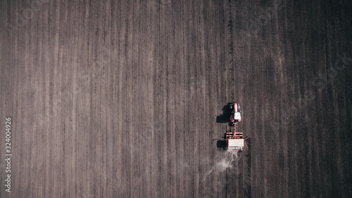 Aerial view of beautiful agriculture landscape and tractor on the field, harvesting the wheat from the soil.
