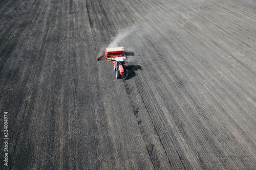 Aerial drone view of farming tractor plowing a wheat field in summer. Agriculture Industry Equipment.