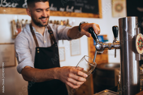 Fotografie barman pouring beer from tap in bar