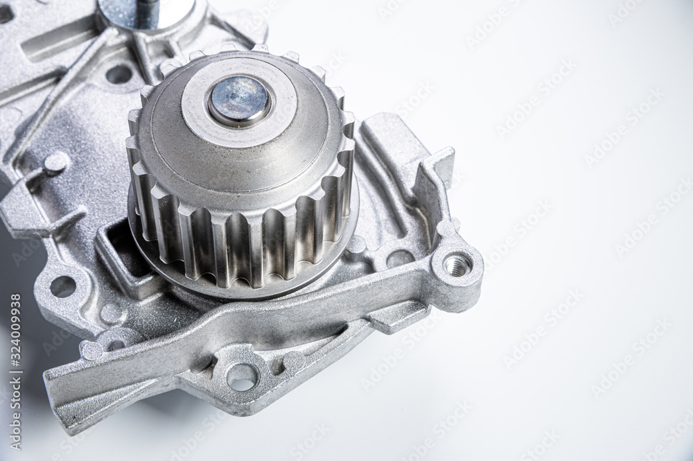 Close-up New metal automobile pump for cooling the engine of a water pump on a gray background. The concept of new spare parts for the car engine Close-up New metal automobile pump for cooling the engine of a water pump on a gray background. The concept of new spare parts for the car engine