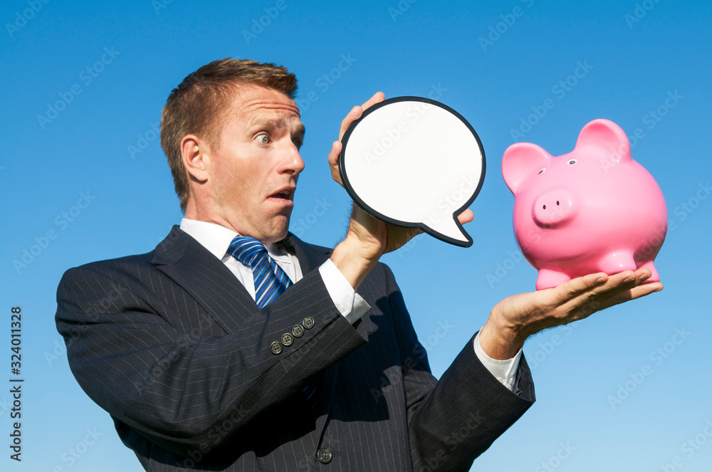 Surprised business man holding a blank speech bubble out for a message from a pink piggy bank Surprised business man holding a blank speech bubble out for a message from a pink piggy bank
