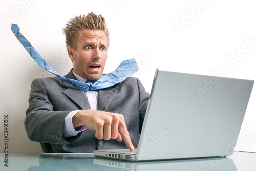 Stressed businessman desperately trying to press the delete button on his laptop computer