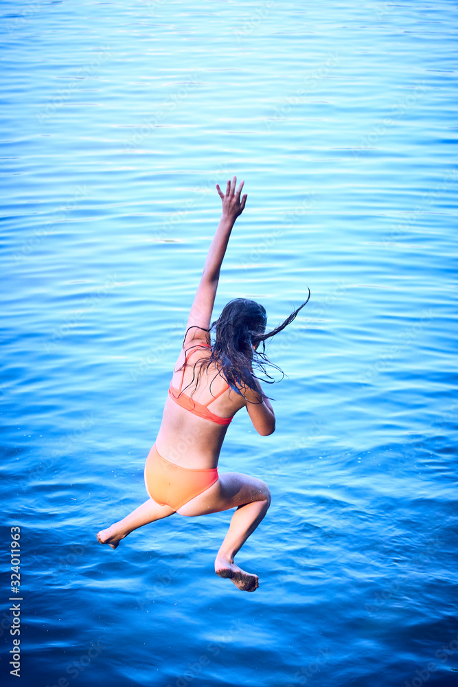 Girl in a swimsuit is jumping into the water