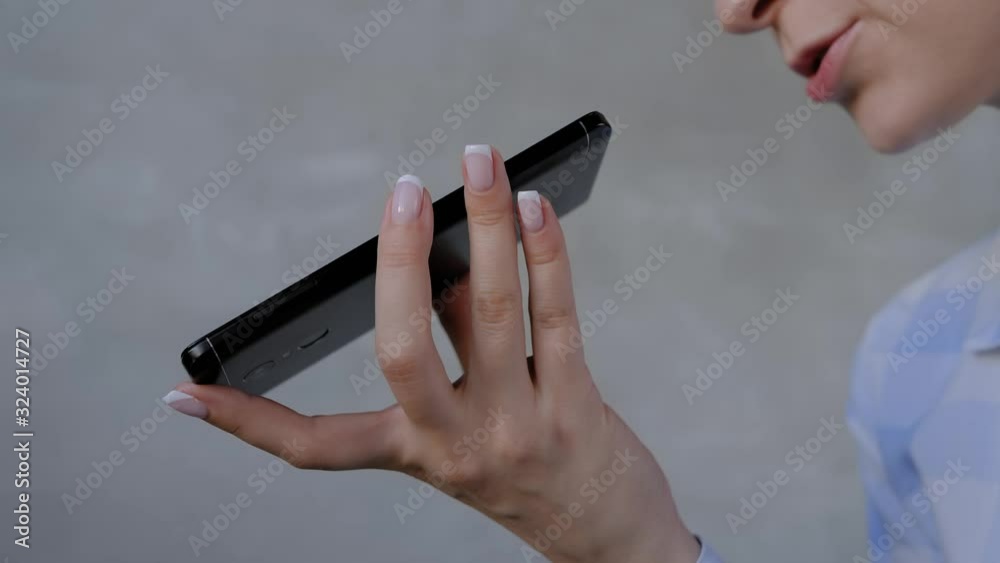 Authentication, communication, online technology concept. Woman holding smartphone device, using voice recognition function, recording audio message or talking with mobile assistant - slow motion