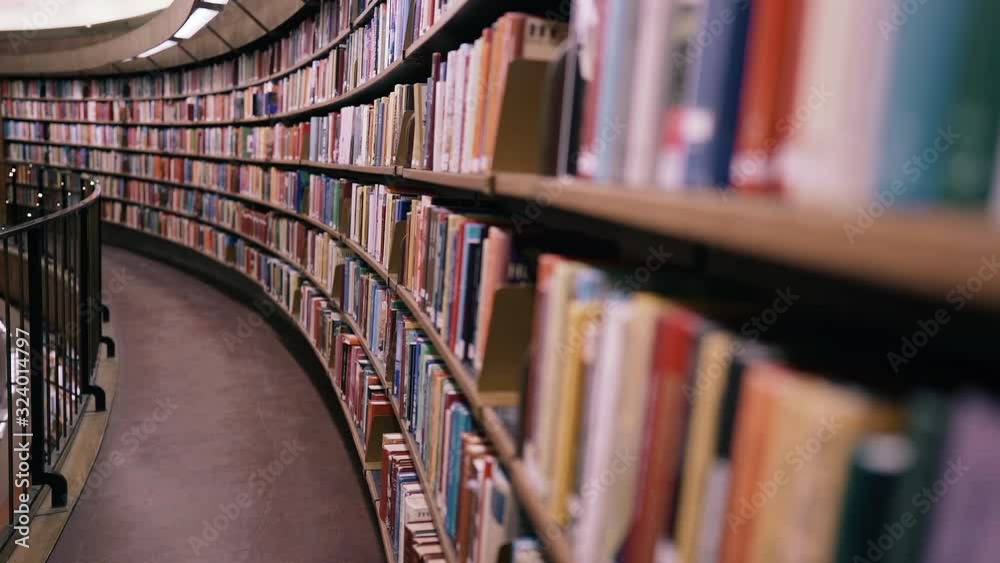 Stedicam shot. Camera moves forward along shelves filled with paper books. The huge round library in Stockholm, Sweden