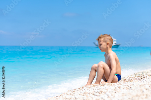 A boy is sitting and looking on the water © Jovan