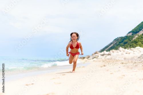 Cute little girl is running by the water