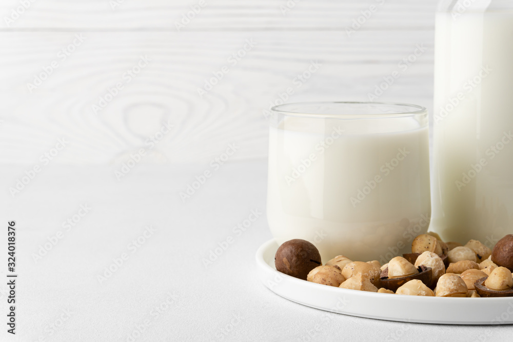 Dairy-free milk. Macadamia nut milk in a glass cup on a white background. Dairy products without lactose. Copy space, close-up. Dairy-free milk. Macadamia nut milk in a glass cup on a white background. Dairy products without lactose. Copy space, close-up.