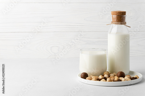 Dairy-free milk. Macadamia nut milk in a glass cup and a bottle on a white background. Dairy products without lactose. Copy space.