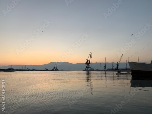 Silhouettes of the sea port cranes background at the sunset, natural colors