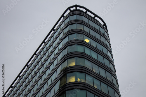 Fragment of the facade of a modern glass skyscraper with reflections and a lantern on the background of a cloudy sky with copy space