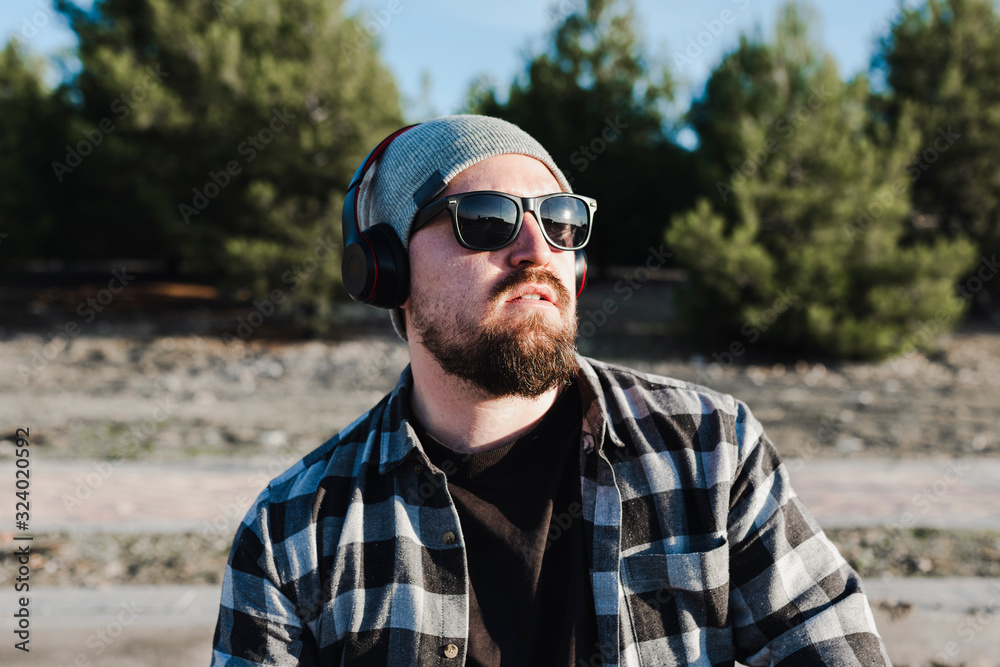 Modern young man with sunglasses, wool hat and headphones Modern young man with sunglasses, wool hat and headphones