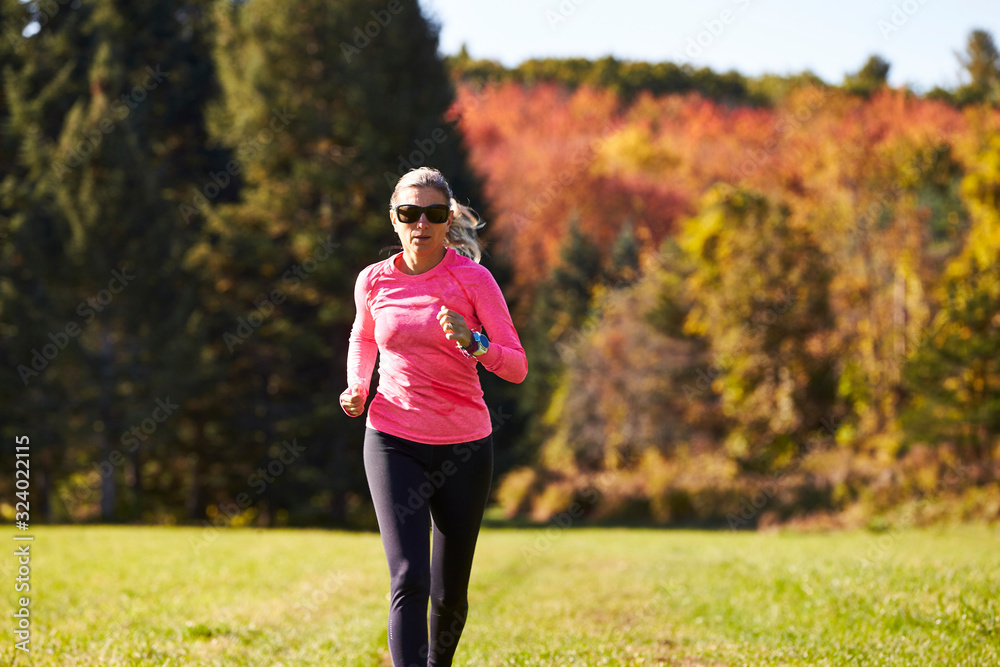 A close up of a woman trail running on an autumn day. A close up of a woman trail running on an autumn day.