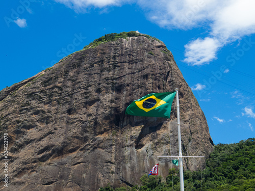 Brazilian flag, fluttering in the wind, against the background of the Sugarloaf Mountain, in Rio de Janeiro. Translation - order and progress.