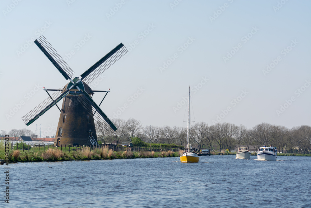 Waterways of North Holland with boats and view on traditional Dutch mill, spring landscape