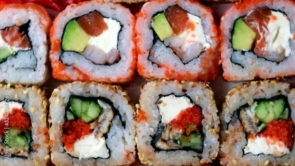 Fresh Sushi roll set rotating. Typical Japanese food, dish consisting of rice, avocado, salmon, tuna, shrimp, soy, fish, caviar. Japan restaurant menu, California set. View from above, Top view, slow Fresh Sushi roll set rotating. Typical Japanese food, dish consisting of rice, avocado, salmon, tuna, shrimp, soy, fish, caviar. Japan restaurant menu, California set. View from above, Top view, slow
