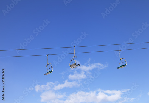 Sunlit ski-lift and blue sky with clouds at ski resort on winter photo