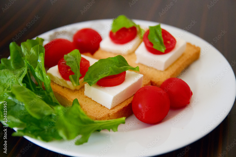 Beautiful breakfast: toasts with goat cheese, tomatoes and Basil on a white plate Beautiful breakfast: toasts with goat cheese, tomatoes and Basil on a white plate