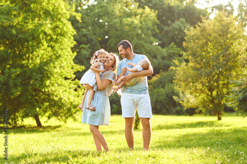 Family with baby stands on grass in the park
