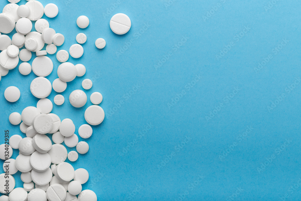 scattered white pills on a blue table. Layout for special offers such as advertising or other ideas. The concept of medicine, pharmacy and healthcare. Space for copy. flat lay for text or logo. scattered white pills on a blue table. Layout for special offers such as advertising or other ideas. The concept of medicine, pharmacy and healthcare. Space for copy. flat lay for text or logo.