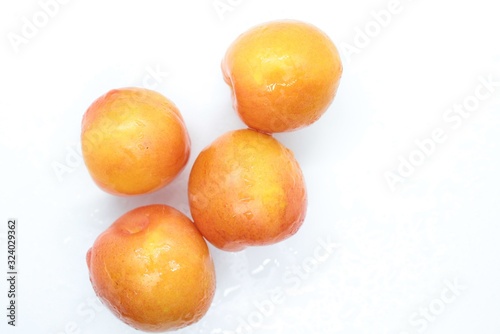 Beautiful delicious orange plums are located on a white background © YURY