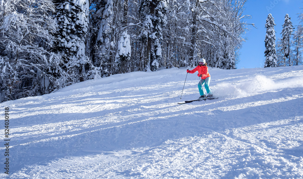 female skier in a bright jacket rides on a ski track. The concept of sport and recreation. Copy space